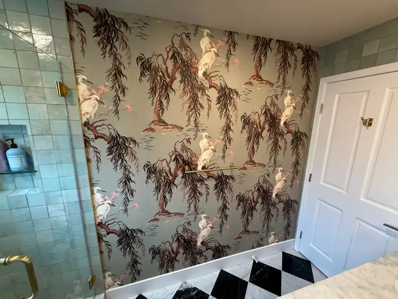 Bathroom wall covered in a willow and heron print next to a glass shower